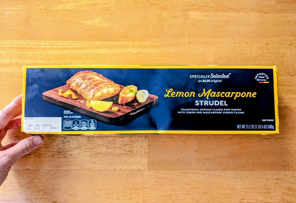 A hand holding a long box of Aldi frozen Lemon Mascarpone Strudel.