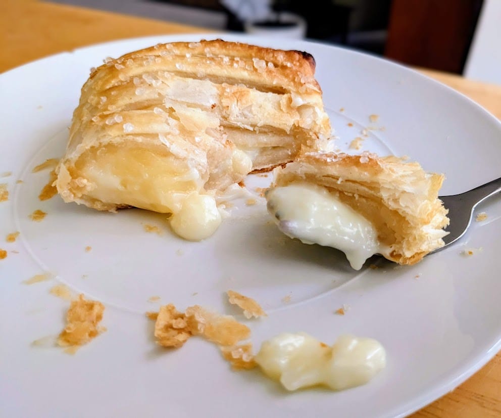 A white plate with a slice of Aldi's Lemon Mascarpone Strudel with a fork bite.