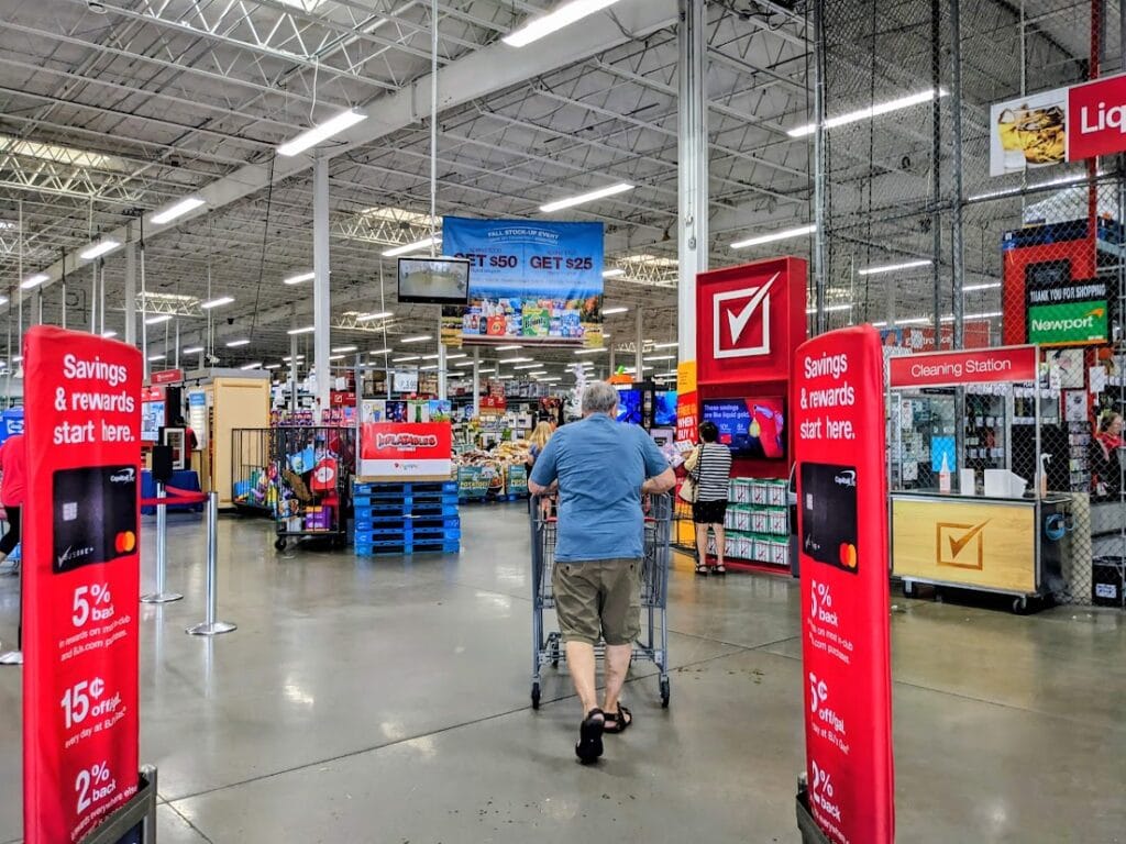 Front entrance of a BJ's Wholesale Club warehouse, with a shopper pushing a cart.