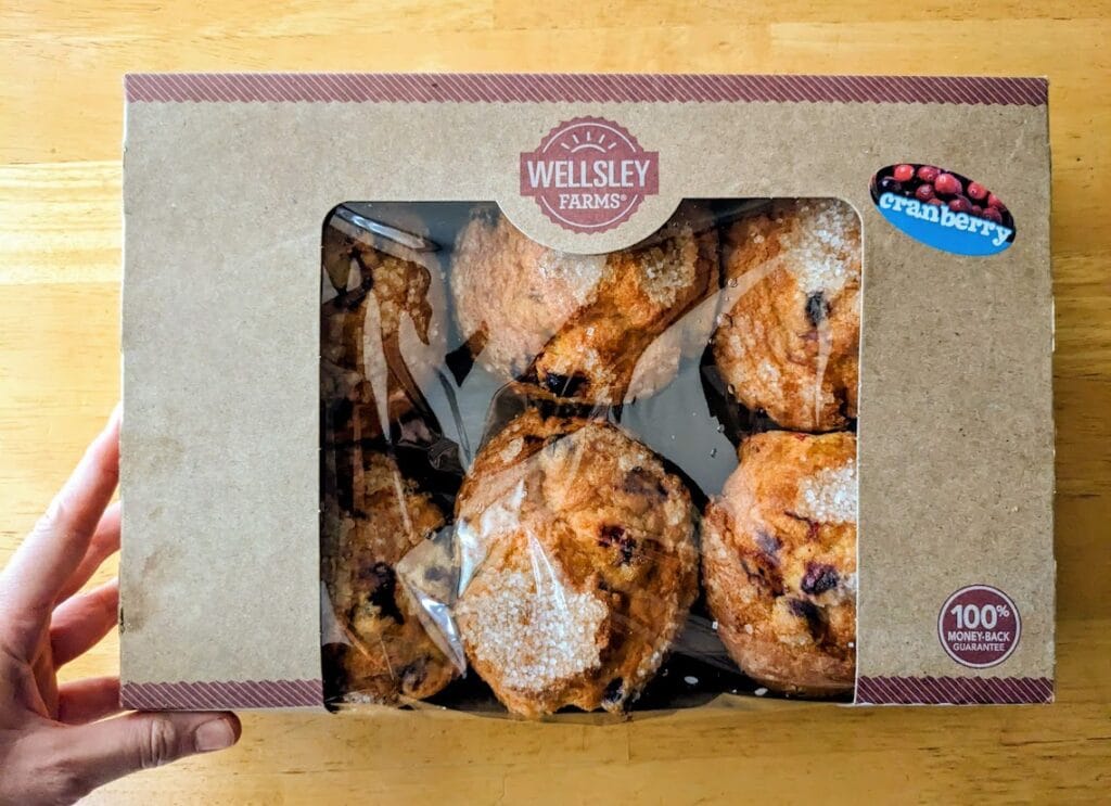 A hand holding a box of cranberry orange muffins from BJ's Wholesale Club.