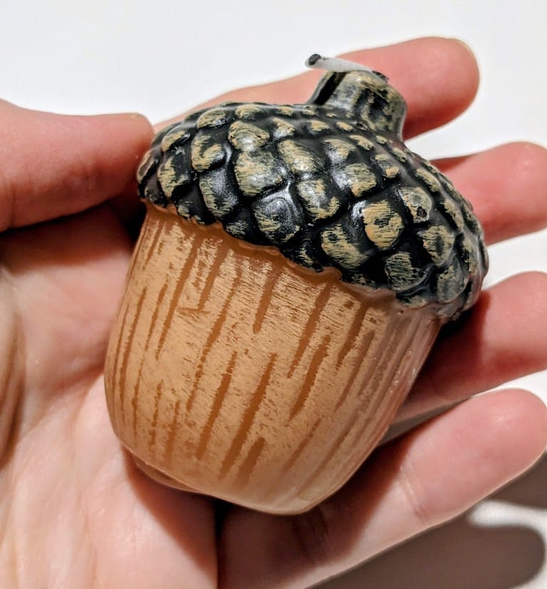 A hand holding an acorn-shaped mini votive candle.