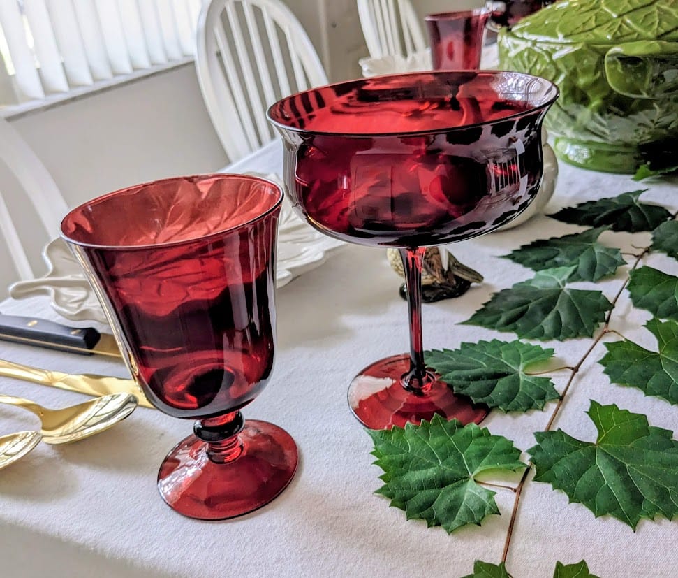 Dark red glasses in two different shapes siting on a holiday dinner table.