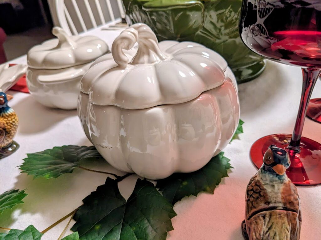 A holiday dinner table with a stoneware pumpkin-shaped baking dish.