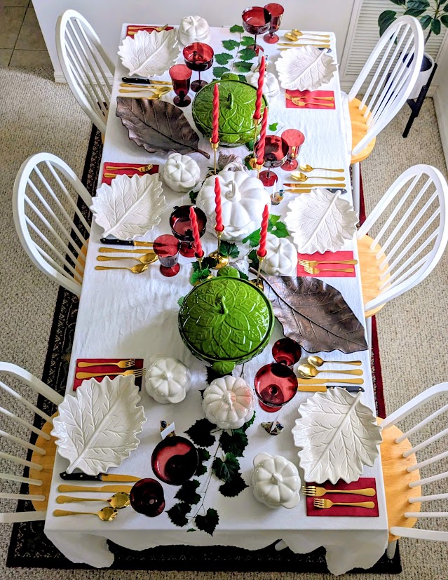Overhead view of a holiday dinner table with red, green, gold, and white dishes.