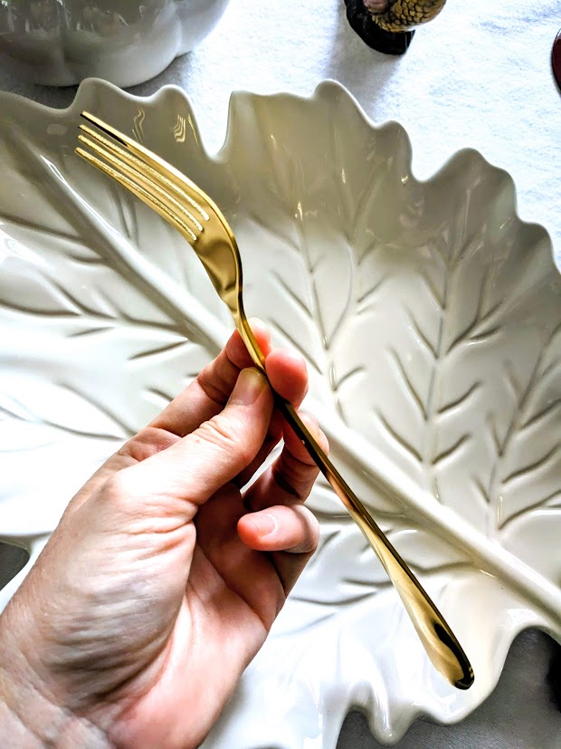 A hand holding a gold fork.