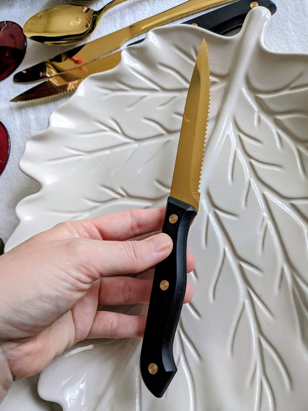 A hand holding a gold steak knife.