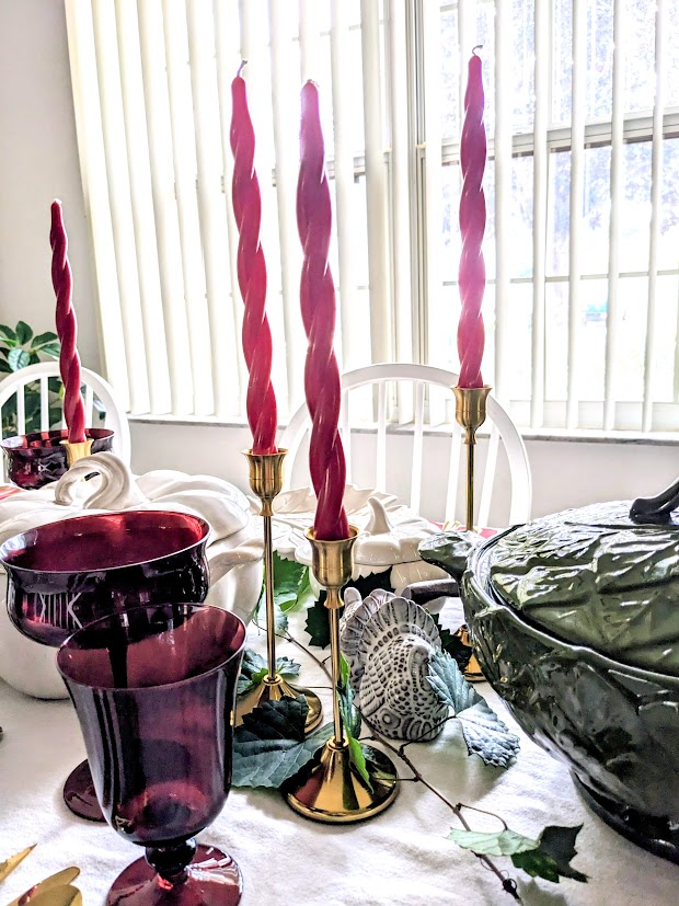 A holiday table with gold candlesticks and red twist tapers.