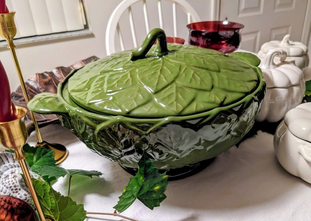 A green leaf tureen sitting on a holiday dinner table.