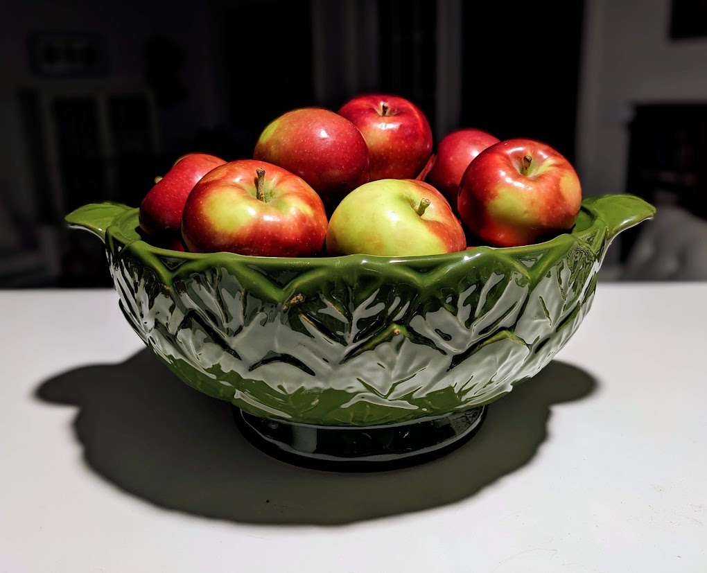 A green leaf bowl filled with red apples.