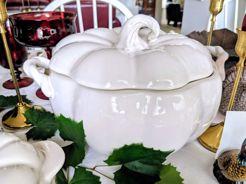 A large pumpkin-shaped stoneware baking dish on a holiday table.