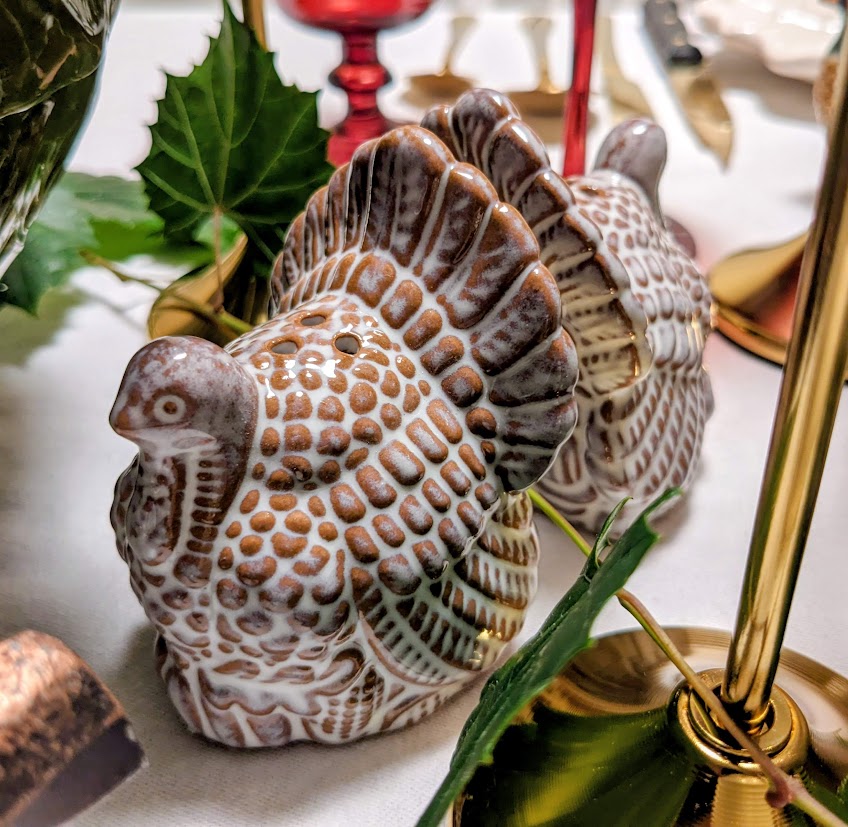 A pair of turkey shaped salt and pepper shakers on a holiday table.